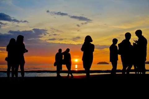 Group of unknown people watching sunset at the beach Stock Photos