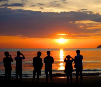 Group of unknown people watching sunset at the beach Stock Photos