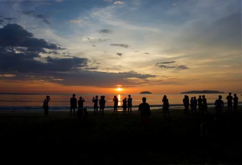 Group of unknown people watching sunset at the beach Stock Photos