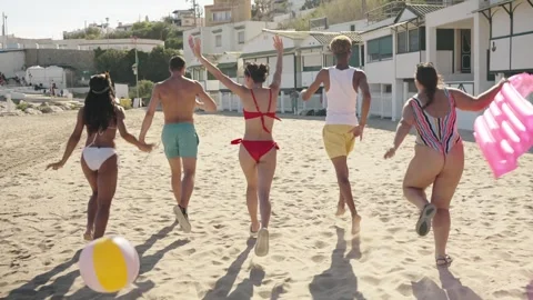 Group of unrecognizable friends with their backs turned excited running along Stock Footage 270535026