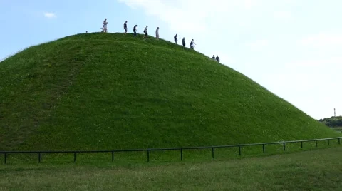 Group of unrecognized people walking down a grassy hill mound Stock Footage 67896515