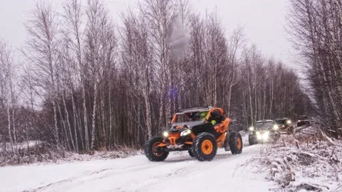 A group of UTV SXS off-road buggies ride through the winter forest and drift Stock Footage 188543010