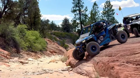 Group of UTVs drop off a red rock ledge in Mount Carmel, Utah Stock Footage 300316658