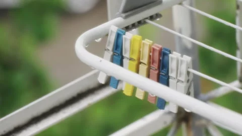 Group of vibrantly colored clothespins on a white drying rack outdoors Stock Footage 314658901