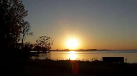 Group walks on park path in front of sunset lake Stock Footage 12370520