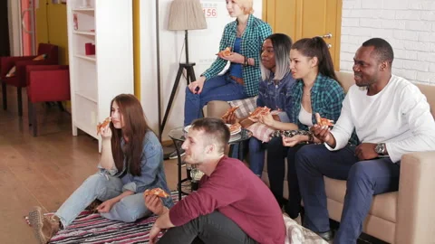 Group watches TV and eats pizza on the couch Stock Footage 89416745