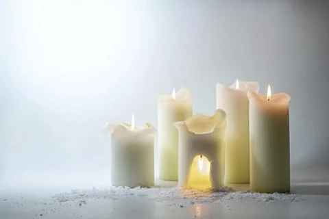 Group of white candles, one is burning overhead in a warm cave, surreal still Stock Photos