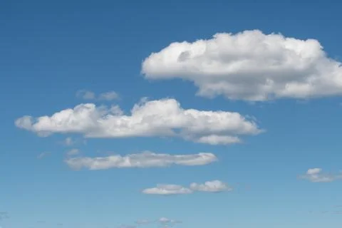 A group of white clouds almost symmetrical between the blue sky and some moun Stock Photos