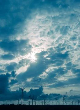 Group of wind turbines in front of dramatic cloudy sky Stock Photos