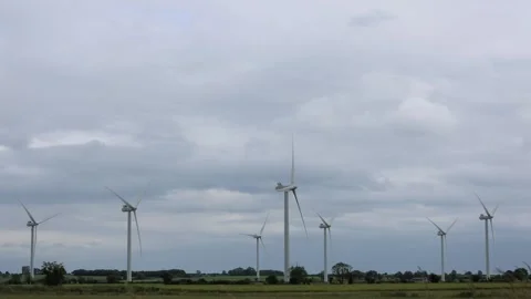 A Group Of Wind Turbines Spinning Among Agricultural Fields On A Cloudy Day Stock Footage 294100278