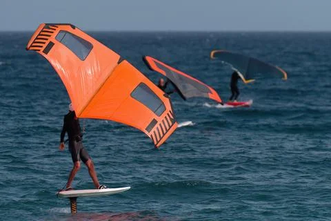 A group is wing foiling using handheld inflatable wings Stock Photos
