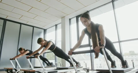 Group of woman in a pilates class working out on reformer machines doing full Stock Footage