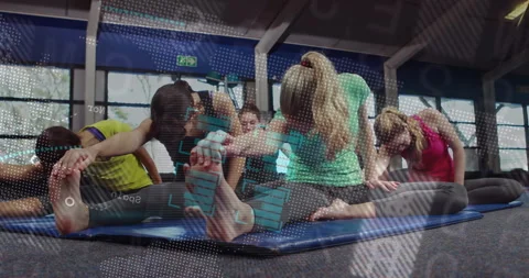 Group of women performing hamstring stretch on blue mats in gym, featuring Stock Footage 307549972
