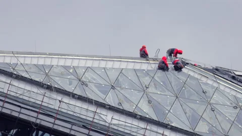 A group of workers are on a building, fixing a window in roof Stock Footage 319839377