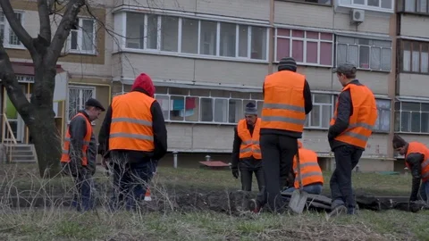 Group of workers digs a hole in the yard of a residential building. Stock Footage 106315065