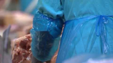 A group of workers at a meat processing plant cuts fresh beef meat into pieces o Stock Footage 111089845