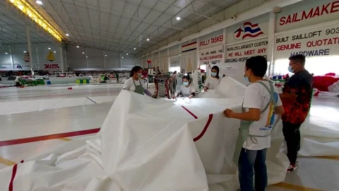 A group of workers move a sail across the table, stitching its parts Vidéo 171223795