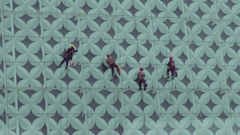 Group of workers in safety gear rappel down a modern building facade with Video stock 335213225