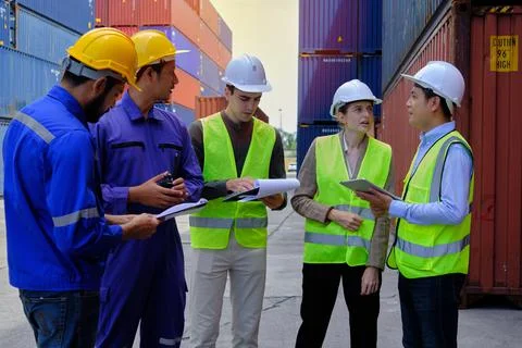 Group of workers teamwork at logistics terminal with many stacks of container Stock Photos