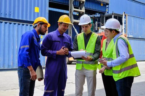 Group of workers teamwork at logistics terminal with many stacks of container Stock Photos