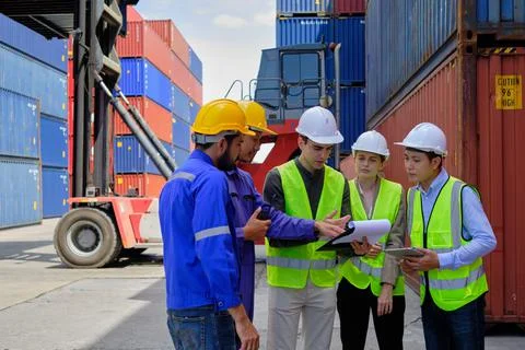Group of workers teamwork at logistics terminal with many stacks of container Stock Photos
