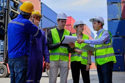 Group of workers teamwork at logistics terminal with many stacks of container Stock Photos