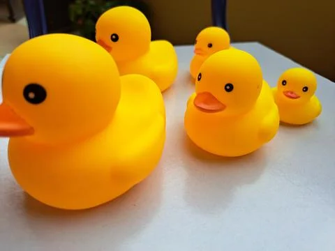 Group of yellow rubber ducks arranged in a line on white table Stock Photos