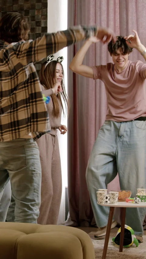 Group of young adults dancing joyfully in a cozy living room, showcasing vibrant Vídeos de archivo 334650497