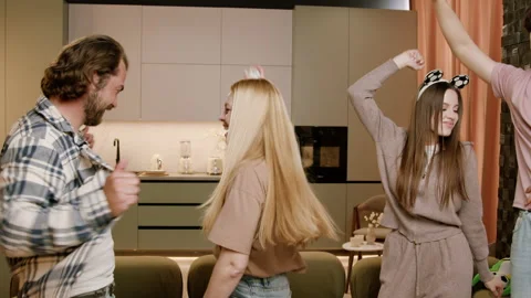 Group of young adults dancing joyfully in a modern kitchen, showcasing fun Видео 335445867