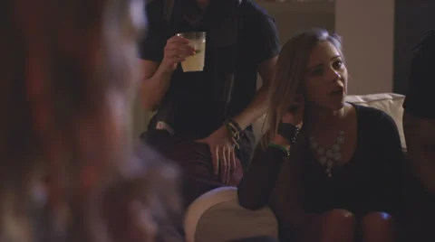 A group of young adults sit together and talk while at a house party Video stock 34016176