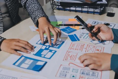 Group of young application developers analyzing uxui mobile app templates d.. Stock Photos