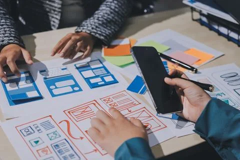 Group of young application developers analyzing uxui mobile app templates d.. Stock Photos