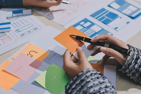 Group of young application developers analyzing uxui mobile app templates d.. Stock Photos
