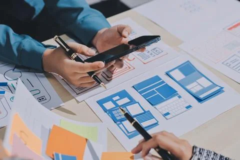 Group of young application developers analyzing uxui mobile app templates d.. Foto stock