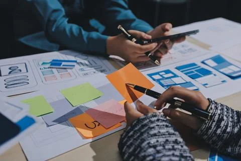 Group of young application developers analyzing uxui mobile app templates d.. Stock Photos