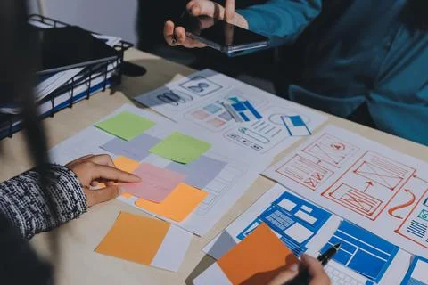 Group of young application developers analyzing uxui mobile app templates d.. Stock Photos