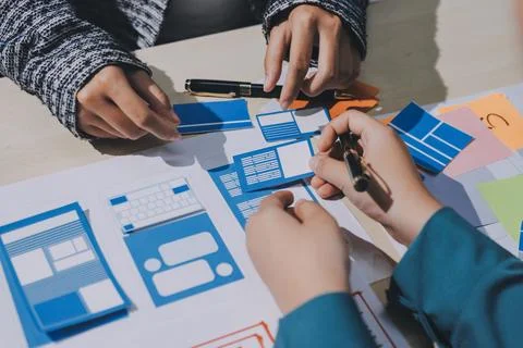 Group of young application developers analyzing uxui mobile app templates d.. Stock Photos