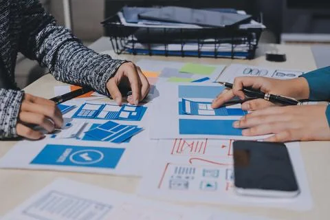 Group of young application developers analyzing uxui mobile app templates d.. Stock Photos