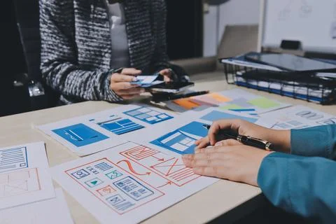 Group of young application developers analyzing uxui mobile app templates d.. Stock Photos