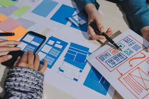 Group of young application developers analyzing uxui mobile app templates d.. Stock Photos