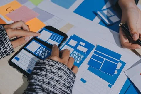 Group of young application developers analyzing uxui mobile app templates d.. Foto stock