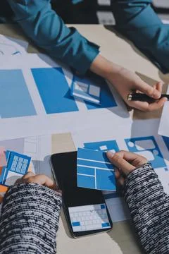 Group of young application developers analyzing uxui mobile app templates d.. Stock Photos