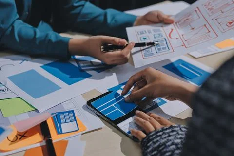 Group of young application developers analyzing uxui mobile app templates d.. Stock Photos