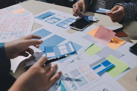 Group of young application developers analyzing uxui mobile app templates d.. Stock Photos