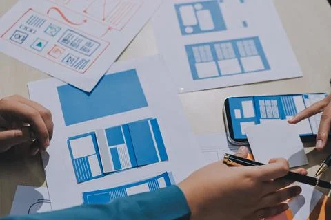 Group of young application developers analyzing uxui mobile app templates d.. Stock Photos