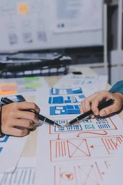 Group of young application developers analyzing uxui mobile app templates d.. Stock Photos