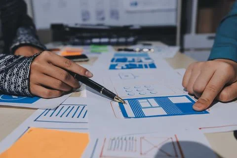 Group of young application developers analyzing uxui mobile app templates d.. Stock Photos