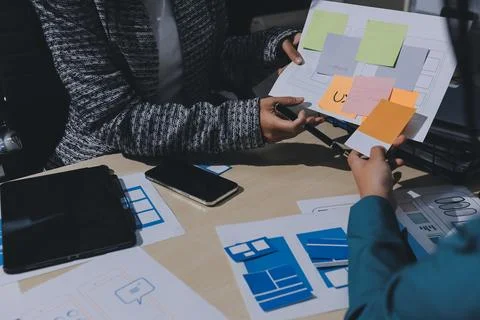 Group of young application developers analyzing uxui mobile app templates d.. Stock Photos