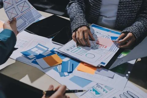 Group of young application developers analyzing uxui mobile app templates d.. Stock Photos