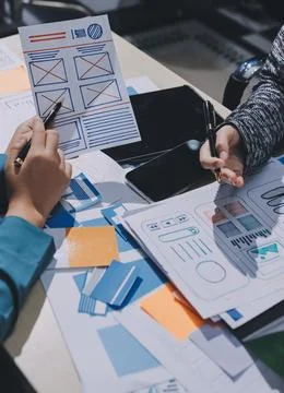 Group of young application developers analyzing uxui mobile app templates d.. Stock Photos